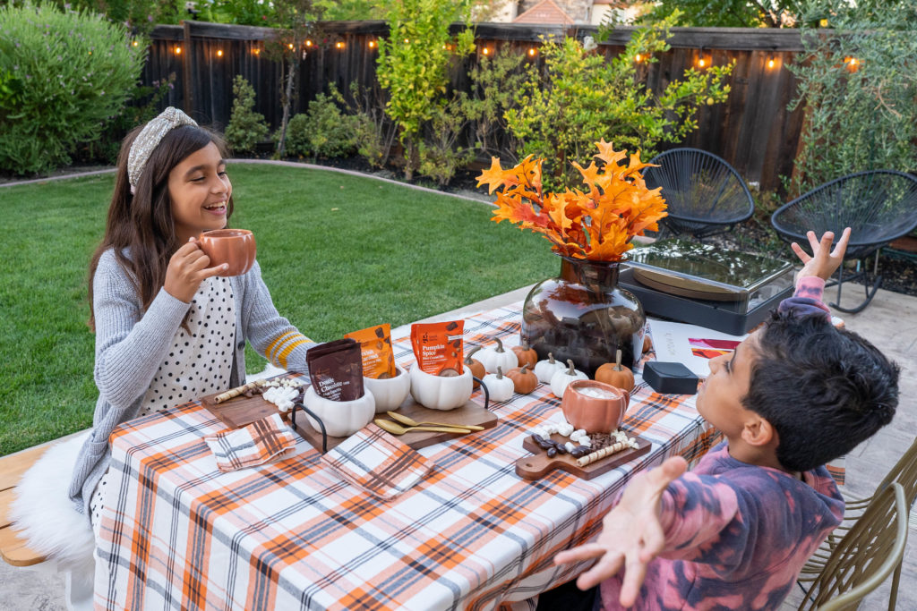 Fall tablescape with boy and girl enjoying hot cocoa. Image also features board and record player- fall leaves and Target finds