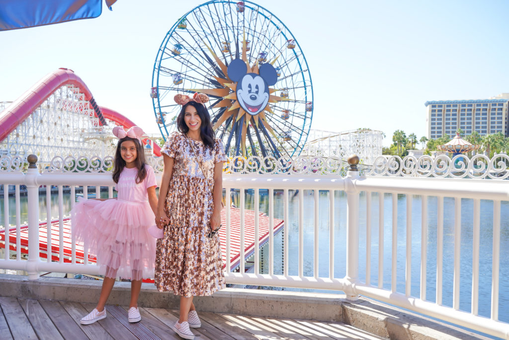 Mother and daughter wearing rose gold outfits in front of the ferris wheel at Disneyland California Adventure