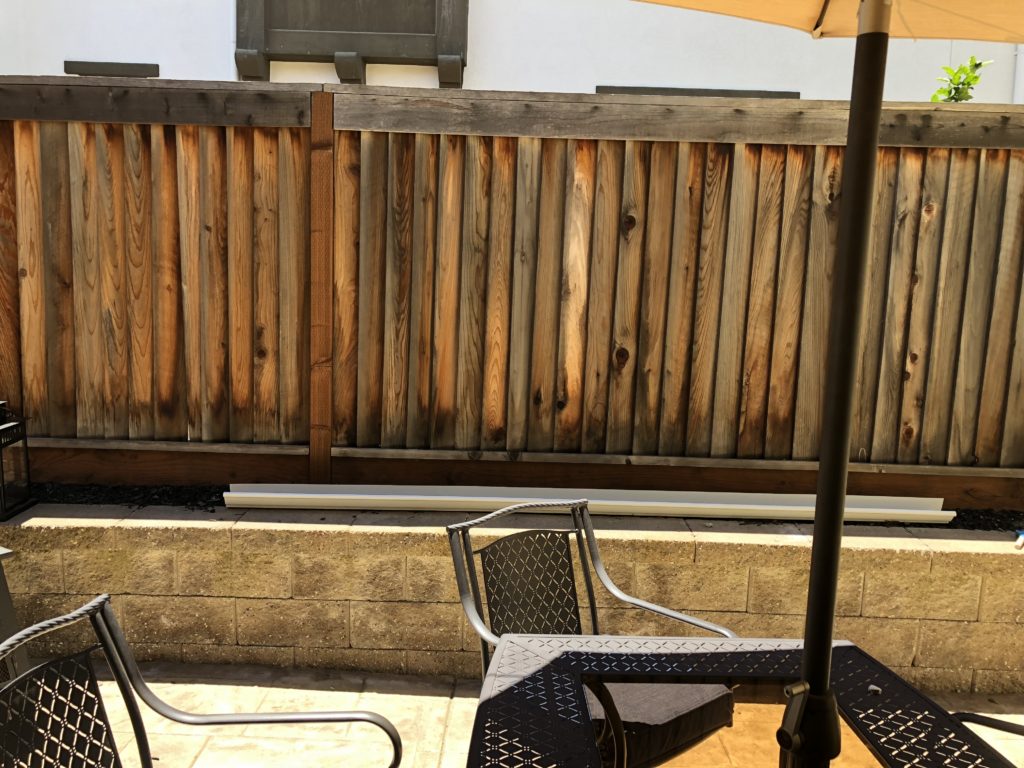 A backyard fence with unsightly cinderblock retaining wall