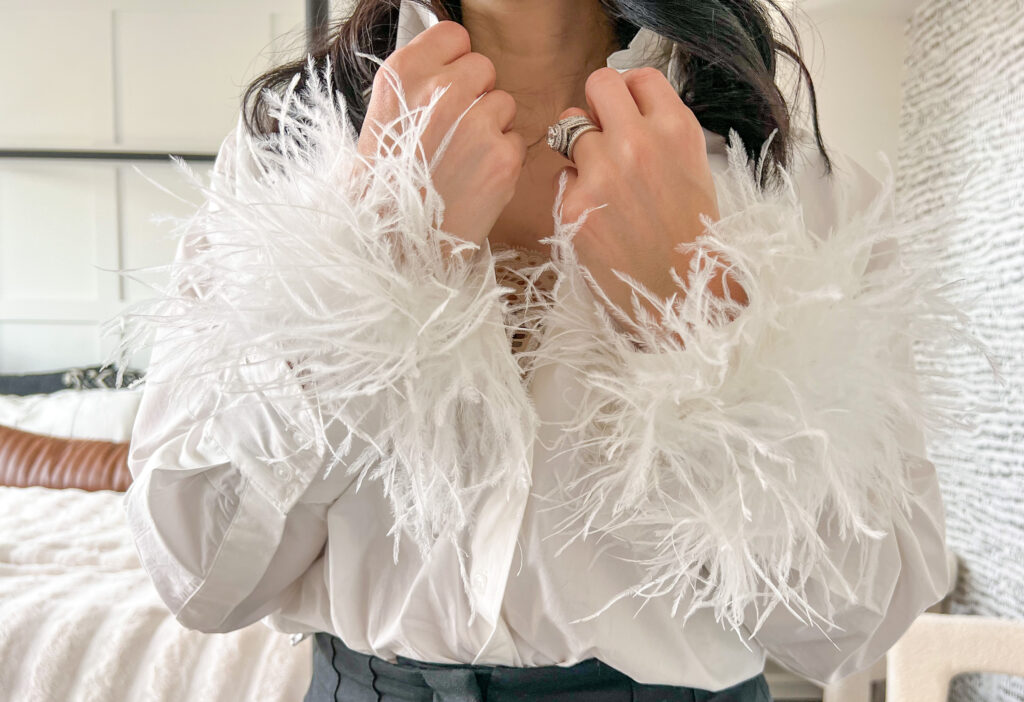 Closeup of brunette woman wearing a white dress shirt with removable feather sleeves