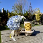 Coffee cup holder with small bouquet and coffee cup with teacher appreciation coffee sleeve that says thank you with smiley face and checker board print in yellow and black