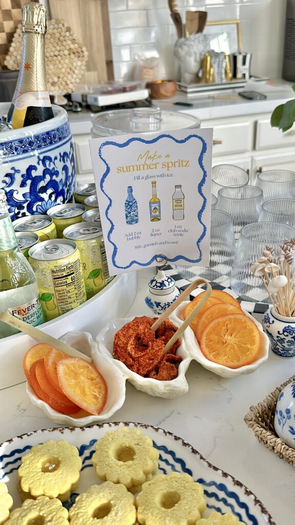 Coastal themed party with shell dishes. A countertop set up with chinoiserie planter used as an ice bucket for a DIY spritz bar. There is an infographic for how to make a summer spritz.